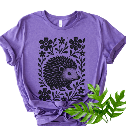 Heather team purple Bella+Canvas 3001 tee with bold hedgehog and floral linocut design, flat lay