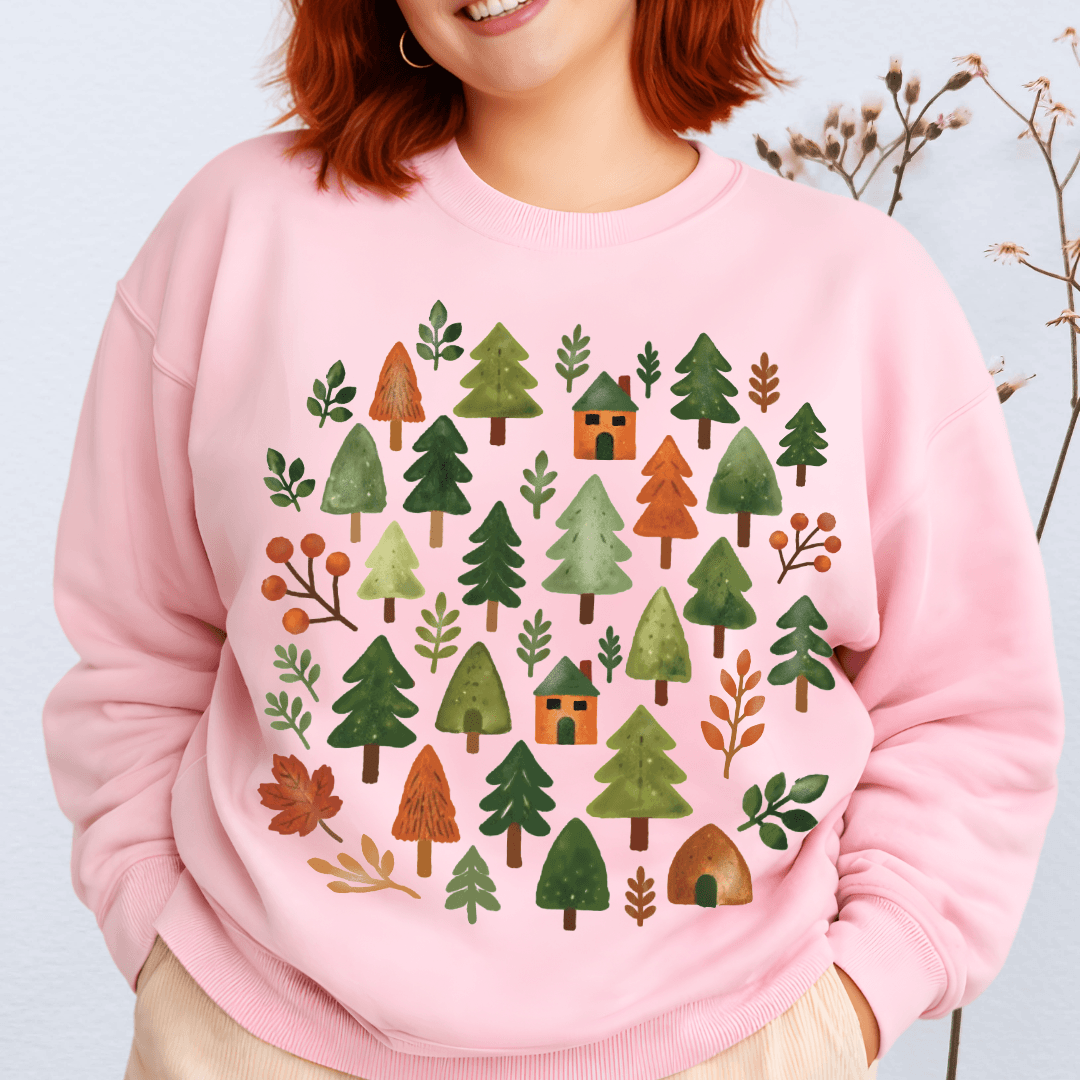 Light pink Gildan 18000 sweatshirt with woodland trees and cabins graphic in warm fall tones
