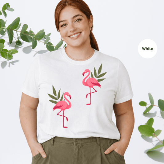 White Bella+Canvas 3001 t-shirt with two hand-painted pink flamingos and tropical leaves graphic